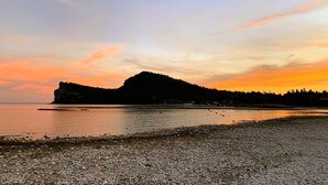 Eine Küstenlandschaft mit felsiger Küste und einem Hügel im Hintergrund.