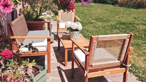 Een terras met houten meubels en een witte parasol.