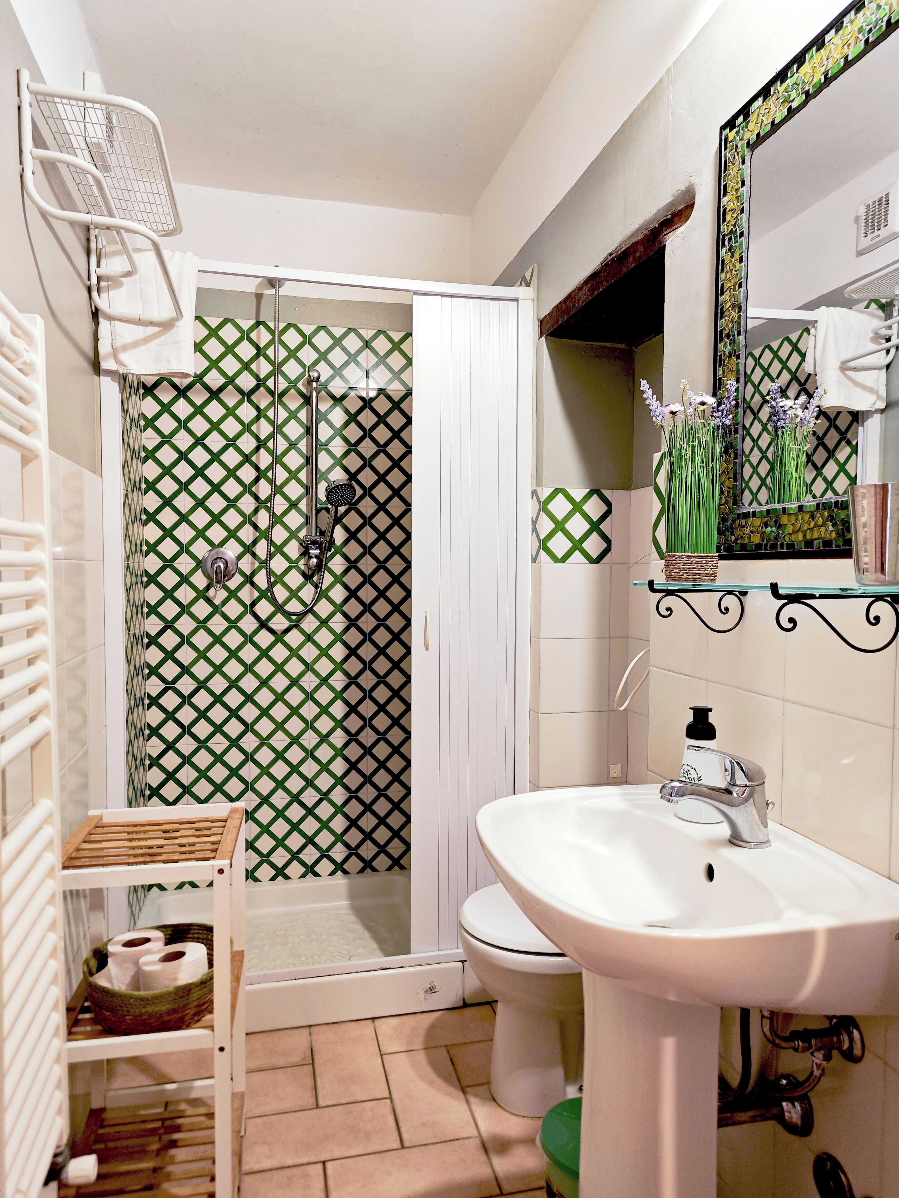 Baño con ducha, inodoro, lavamanos y espejo.