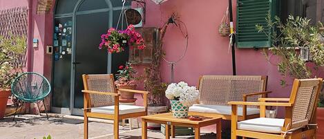 An outdoor seating area with wicker furniture, a white umbrella, and potted plants.