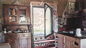 Een rustieke keuken met houten kastjes, een betegelde achterwand en uitzicht op de omgeving.