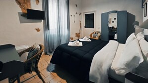 Een hotelkamer met een bed, bureau, stoel, kast en spiegel.