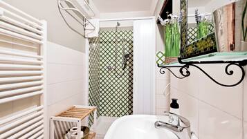 Un baño con un lavabo blanco, una ducha con puerta de diseño blanco y verde, y un toallero blanco.
