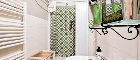 Un baño con un lavabo blanco, una ducha con puerta de diseño blanco y verde, y un toallero blanco.