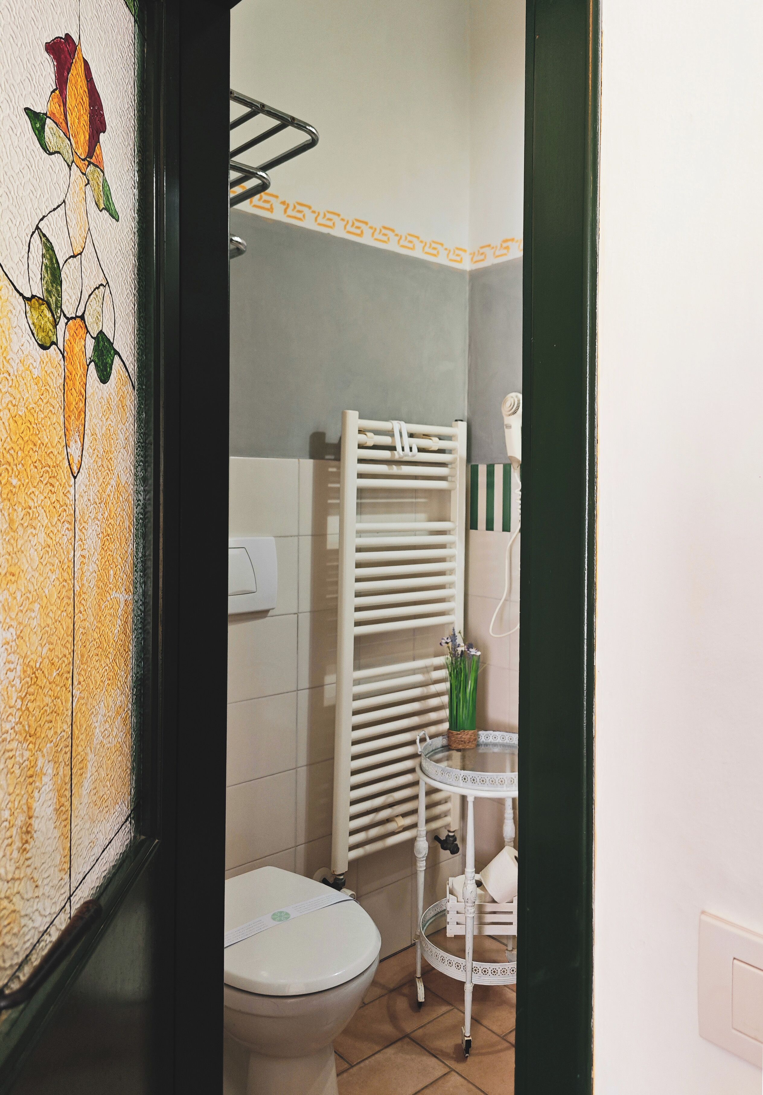 A bathroom with a toilet, a towel rack, and a small table with a plant.