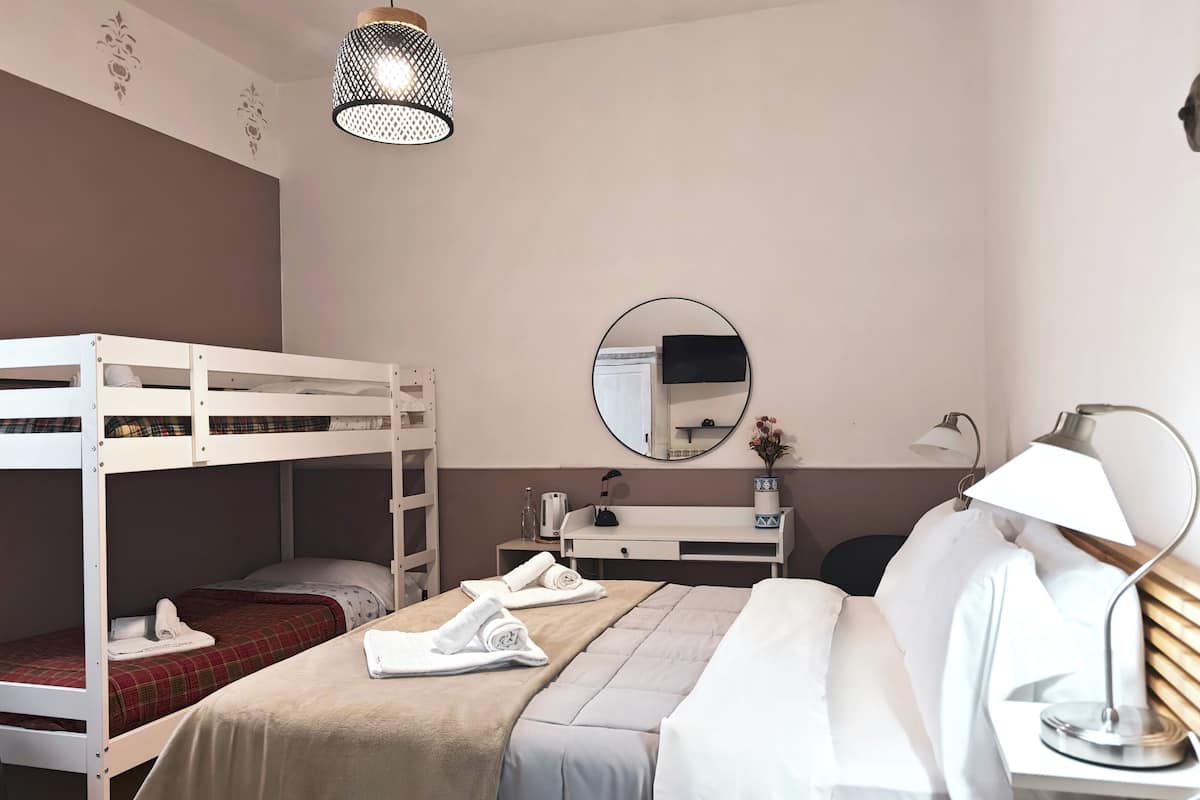 Quarto com beliches, uma escrivaninha com espelho, luminária e mesa de cabeceira.