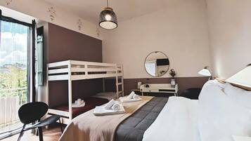 Ett hotellrum med en våningssäng, ett skrivbord med en spegel, en stol och en säng med en stor kudde.