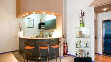 A bar area with a counter, three stools, a fire extinguisher, and a glass display case with bottles.