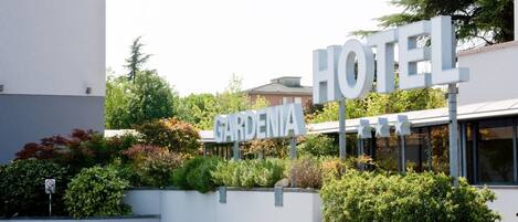 A hotel sign with the name 'GARDENIA' and a parking sign indicating a parking area to the right.