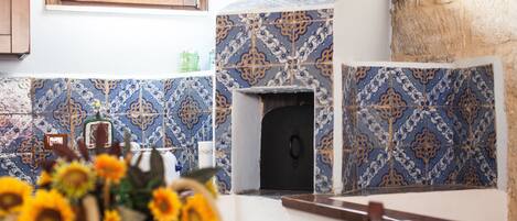 Una cocina con baldosas estampadas, una ventana y un jarrón de girasoles sobre la mesa.