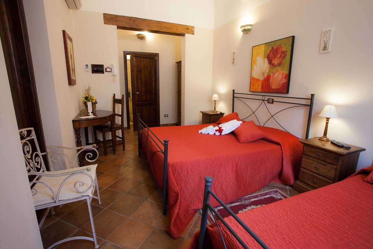 A bedroom with two beds, a desk, and a chair.