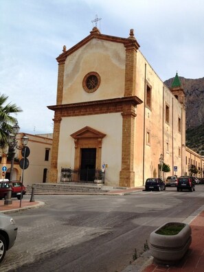 A building with a central entrance, a clock above the door, and a bell tower with a cross on top. - Cinisi Vacanze (Cinisi)