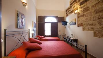 A room with two beds, a desk, a chair, a television, and a window.