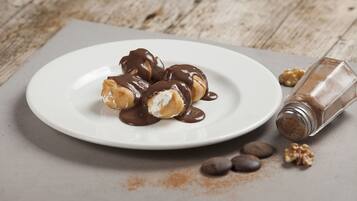 A plate of chocolate-covered pastries on a white plate with a wooden table background.