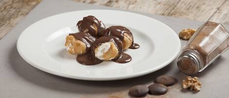 A plate of chocolate-covered pastries on a white plate with a wooden table background.