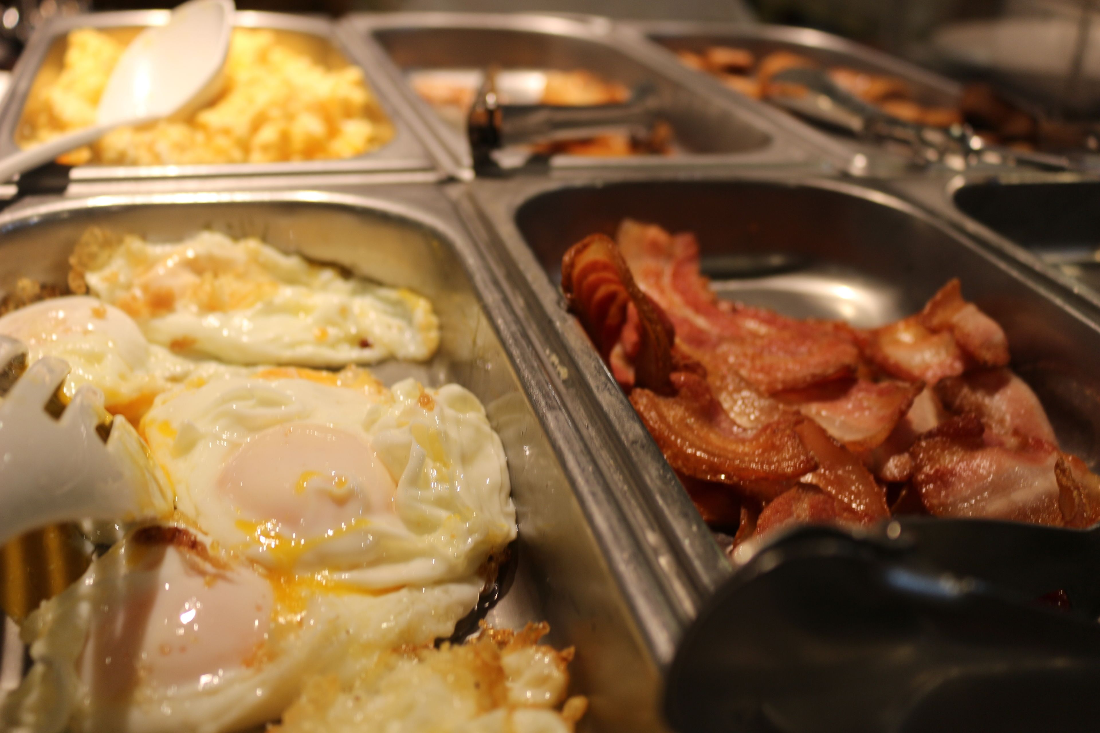A buffet with various breakfast options including eggs and bacon.