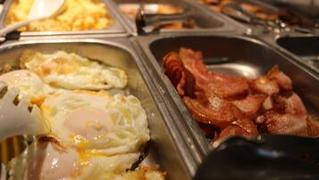 Un buffet proposant différents plats pour le petit-déjeuner, notamment des œufs et du bacon.