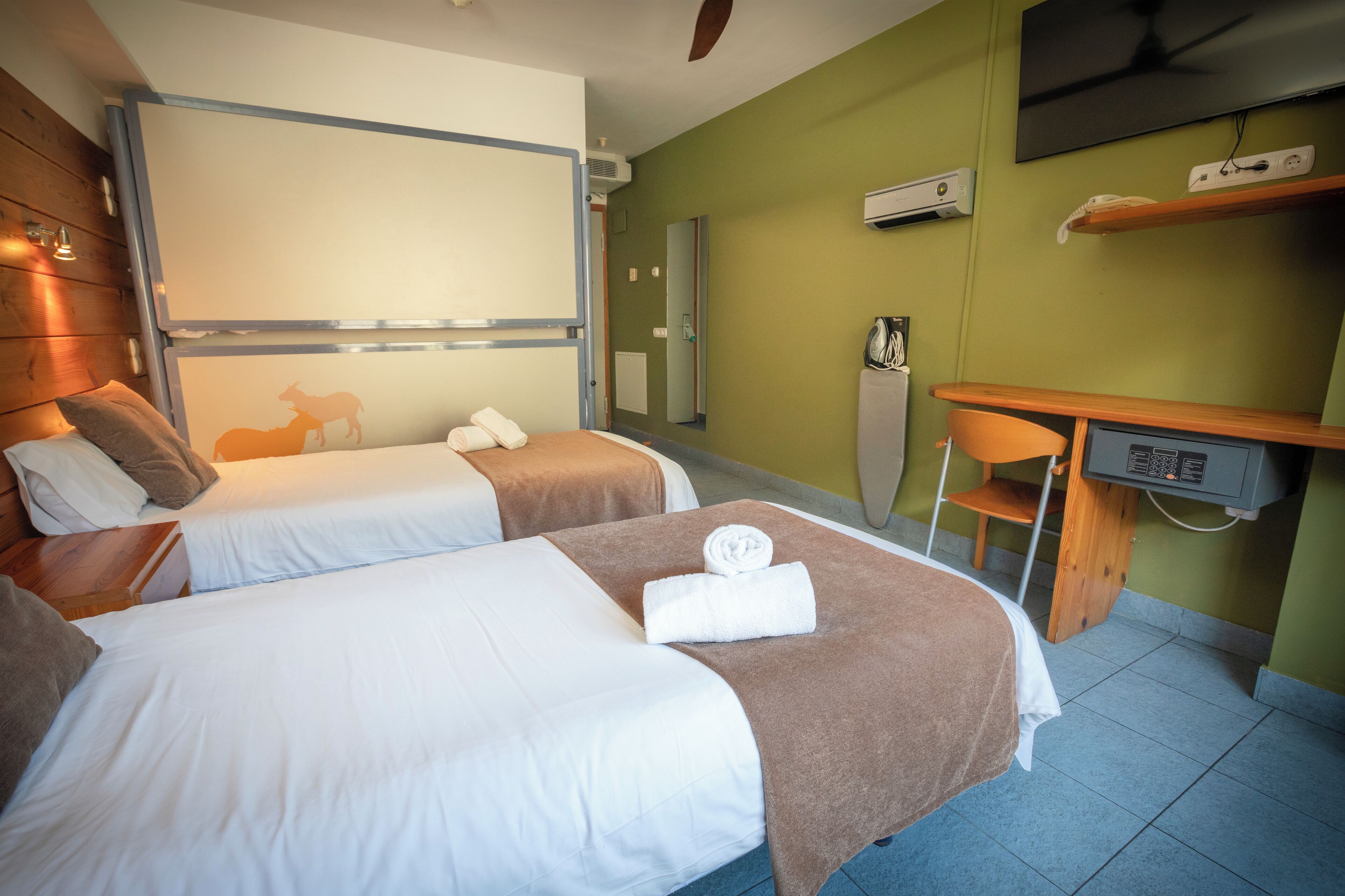 Habitación de hotel con dos camas, un escritorio, una silla, un televisor y un espejo.