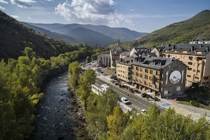 Un hotel con un letrero de restaurante, situado junto a un río con montañas al fondo.