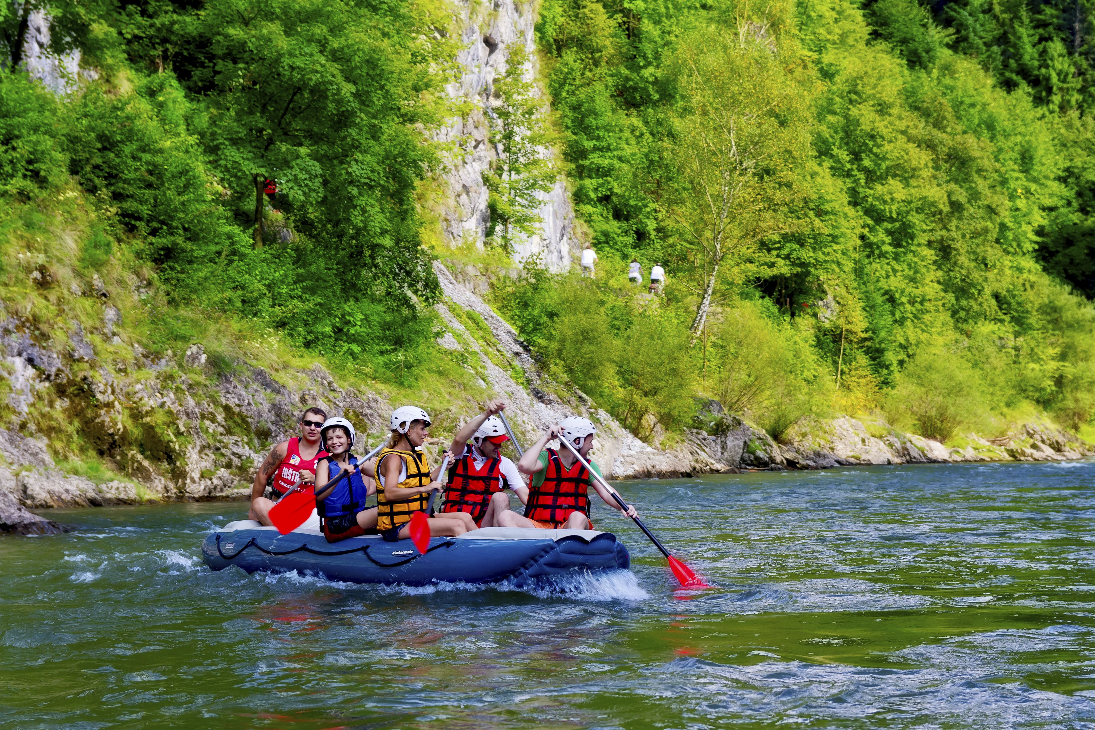 Eine Gruppe von Menschen in einem Floß auf einem Fluss, umgeben von viel Grün.