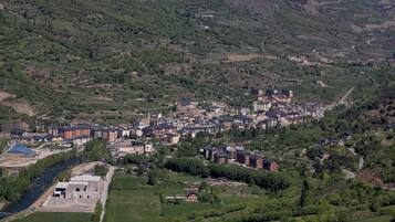 Un pueblo ubicado en un valle, con una combinación de edificios residenciales y comerciales, rodeado de colinas y montañas verdes.