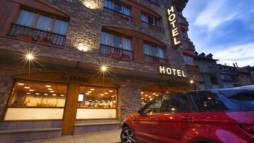 A hotel with a stone facade, multiple balconies with flower boxes, and a sign indicating it is a hotel.