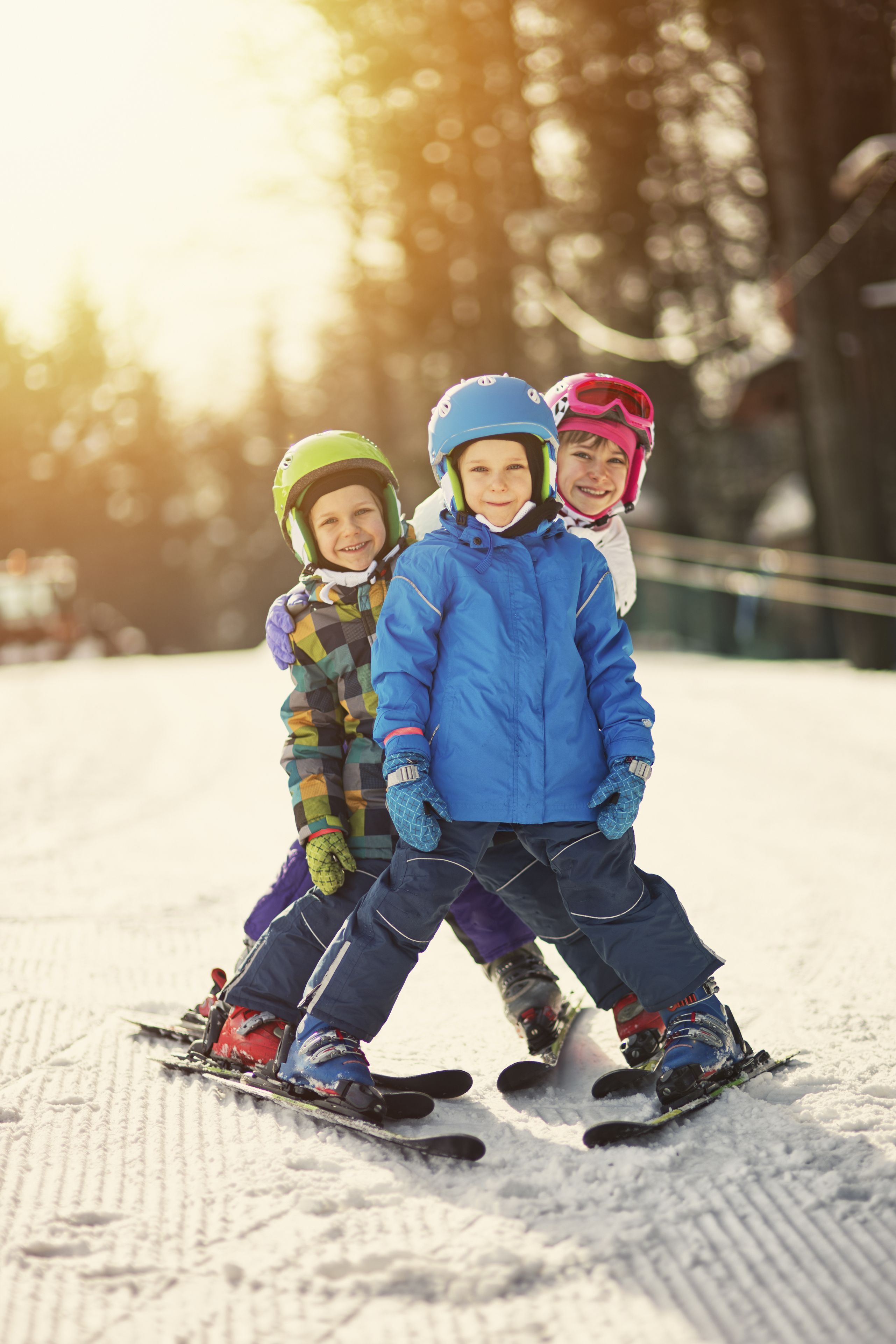Trois enfants font du ski sur une pente enneigée.