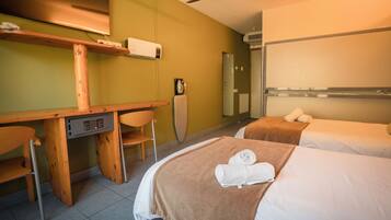 Una habitación de hotel con dos camas, un escritorio, una silla y un ventilador de techo.