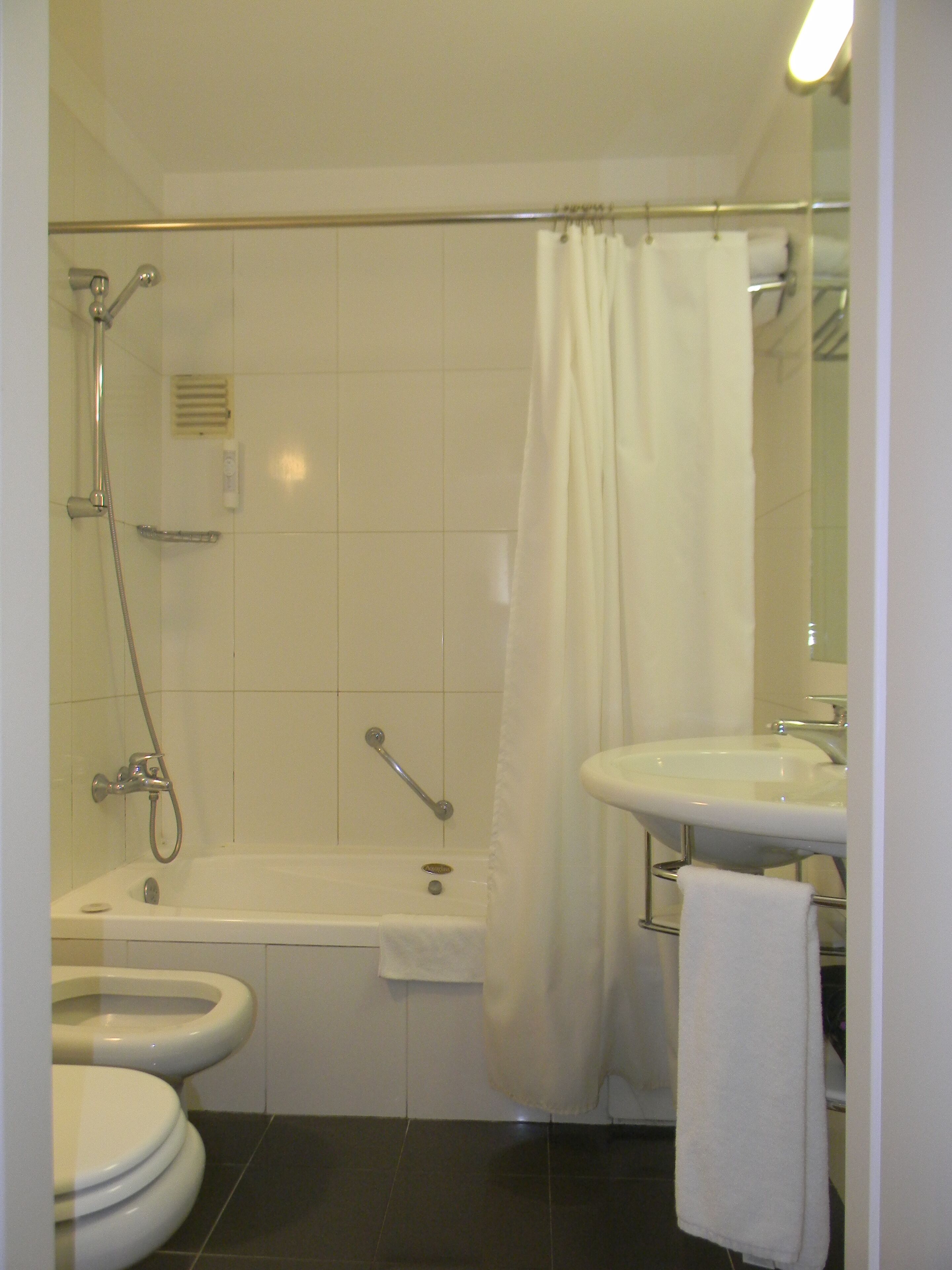 Un baño con bañera, dos inodoros, un lavabo y ducha.