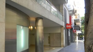 Um edifício moderno com fachada de vidro, uma coluna de metal e uma placa vermelha com o texto "DIO".