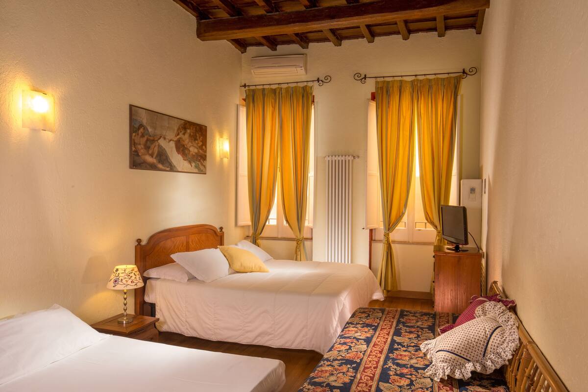 Une chambre d’hôtel avec deux lits, une télévision, un radiateur et un tableau au mur.