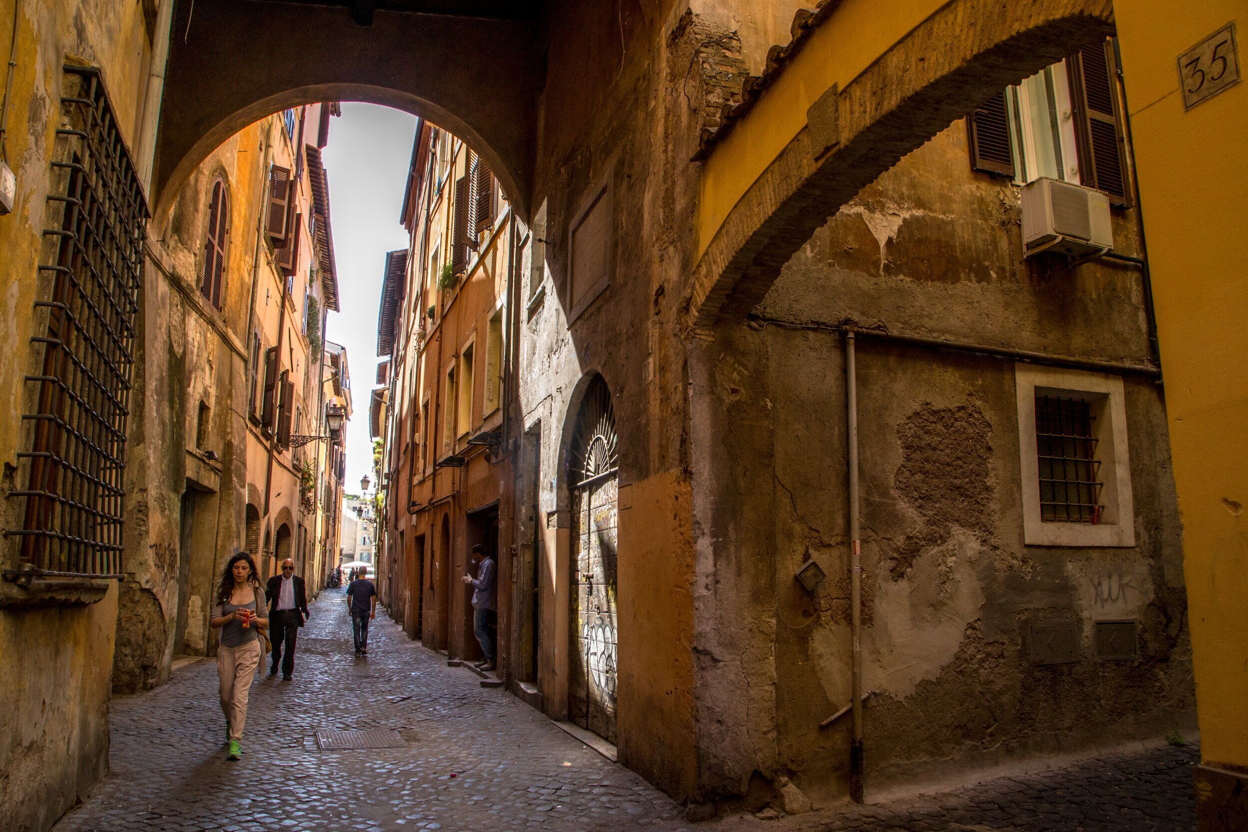A narrow cobblestone street with historic buildings, an archway, and a number '35' sign.