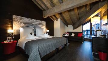 A modern bedroom with a large bed, a sofa, and a view of the city through a large window.
