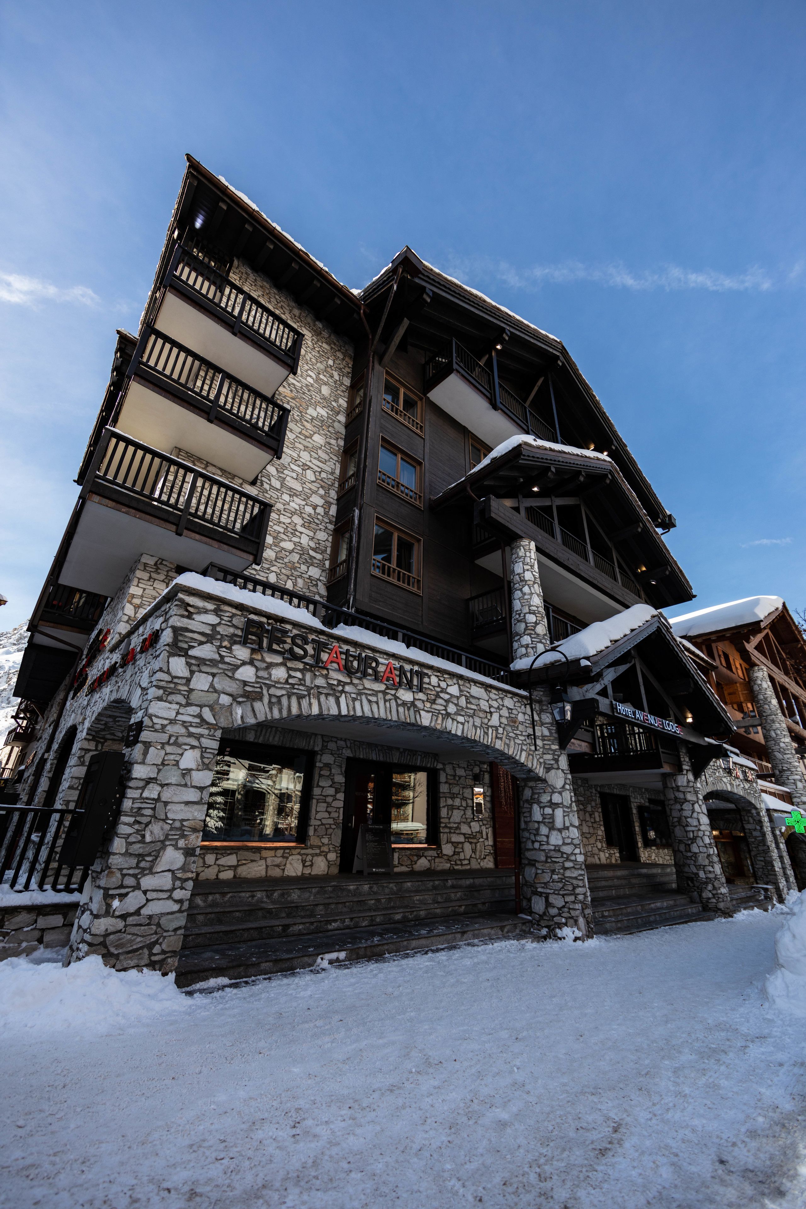 Un immeuble en pierre à plusieurs étages, doté de balcons et d’une enseigne indiquant qu’il s’agit d’un chalet de ski.