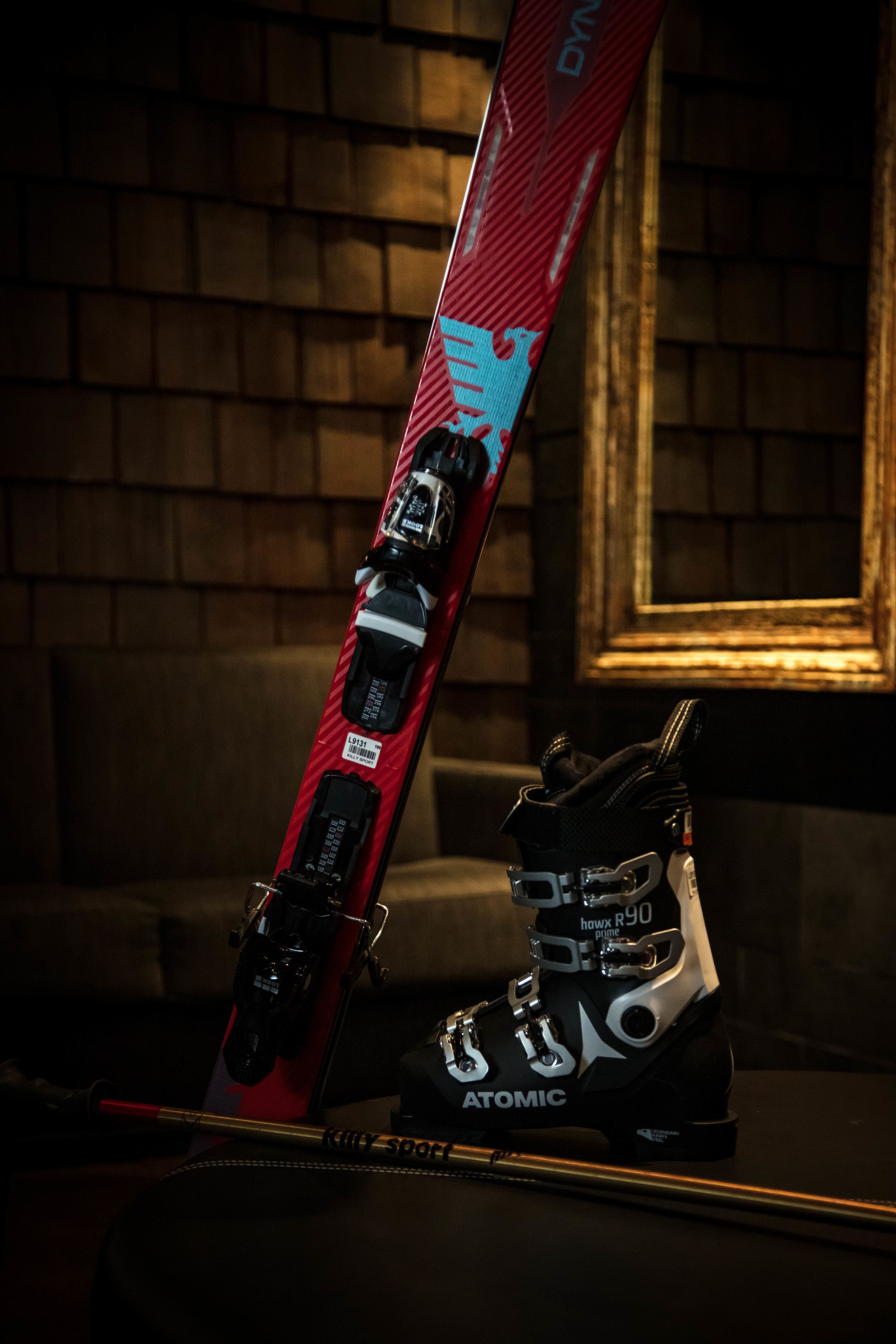 A ski boot and a ski leaning against a wall.