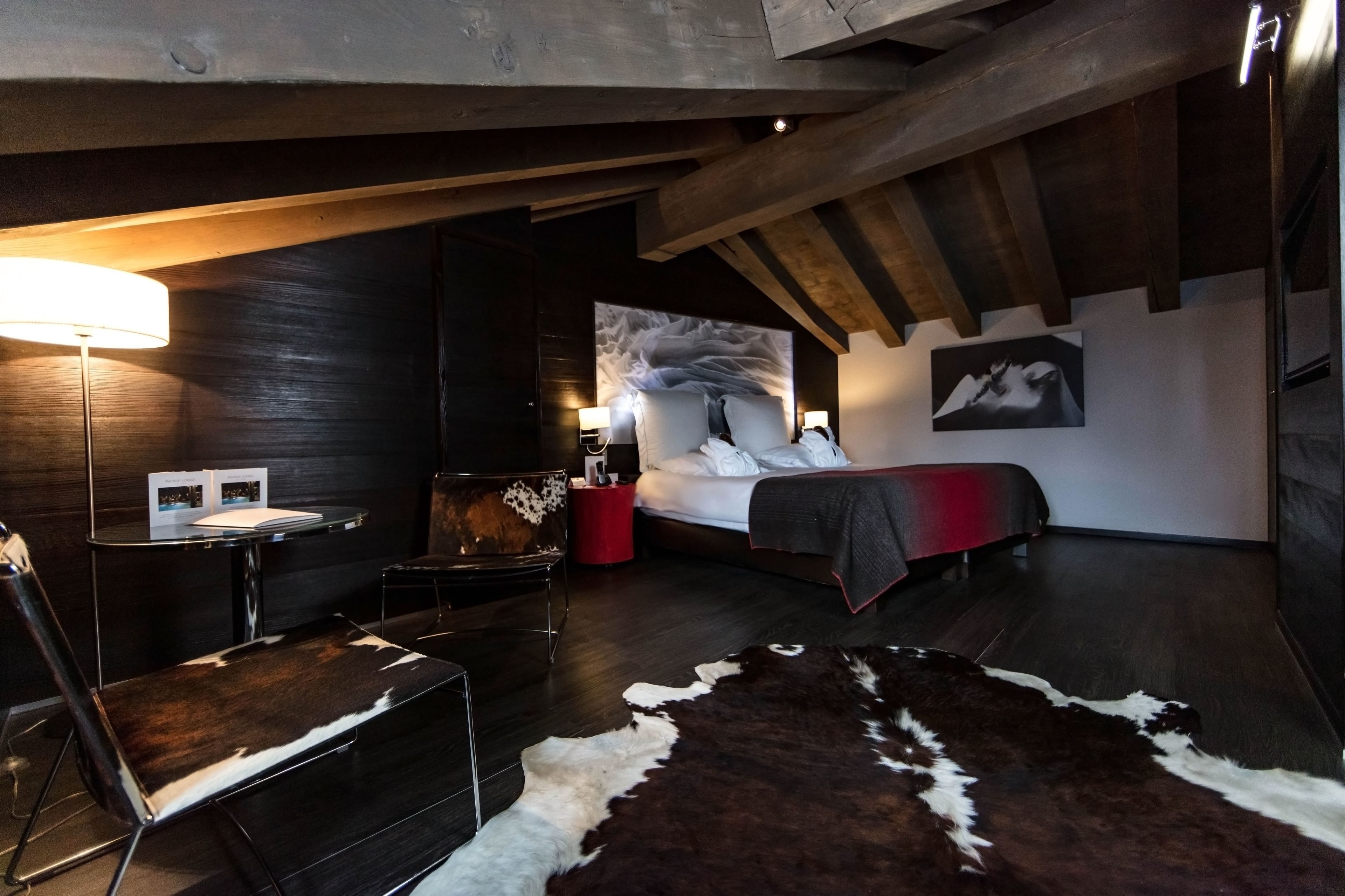 Ein modernes Schlafzimmer mit einem Bett, einem Schreibtisch und einem Stuhl. Auf dem Boden liegt ein Rindellederteppich.