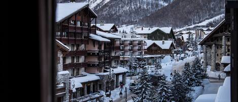 A snowy mountain village with wooden buildings and a view of a mountain.