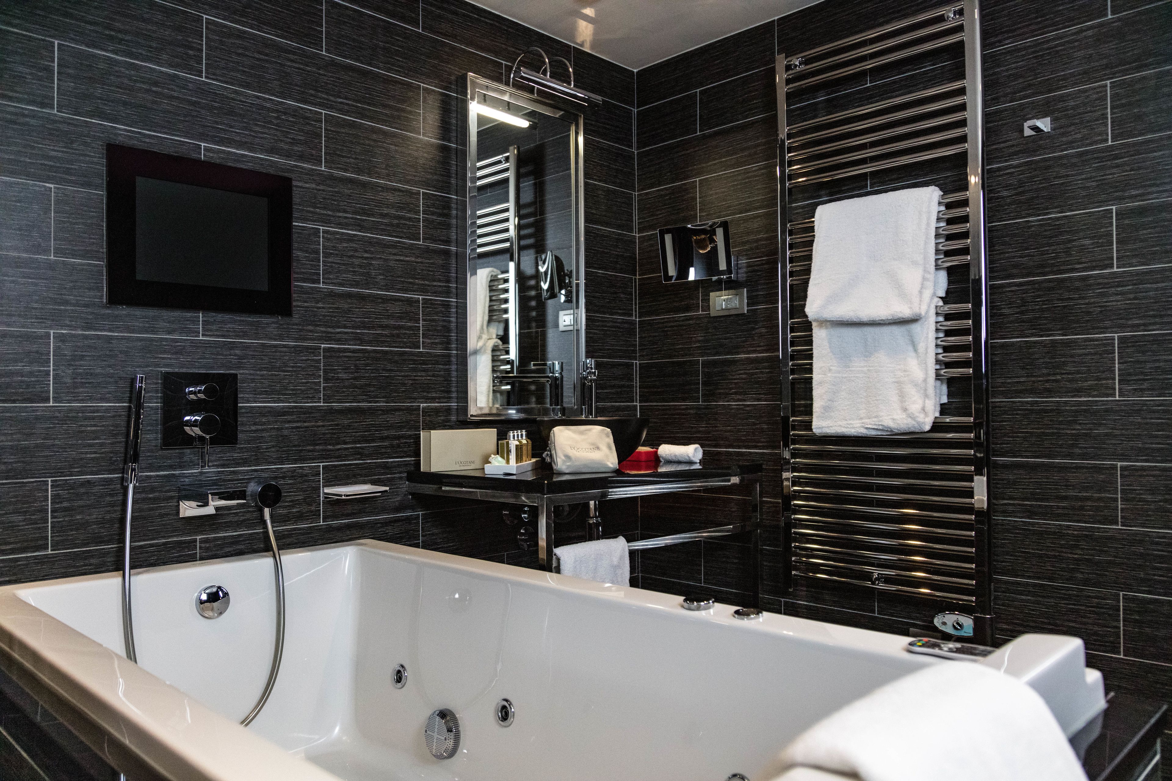A modern bathroom with a large bathtub, a vanity with a mirror, and a towel rack.