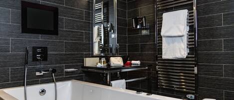 A modern bathroom with a large bathtub, a vanity with a mirror, and a towel rack.