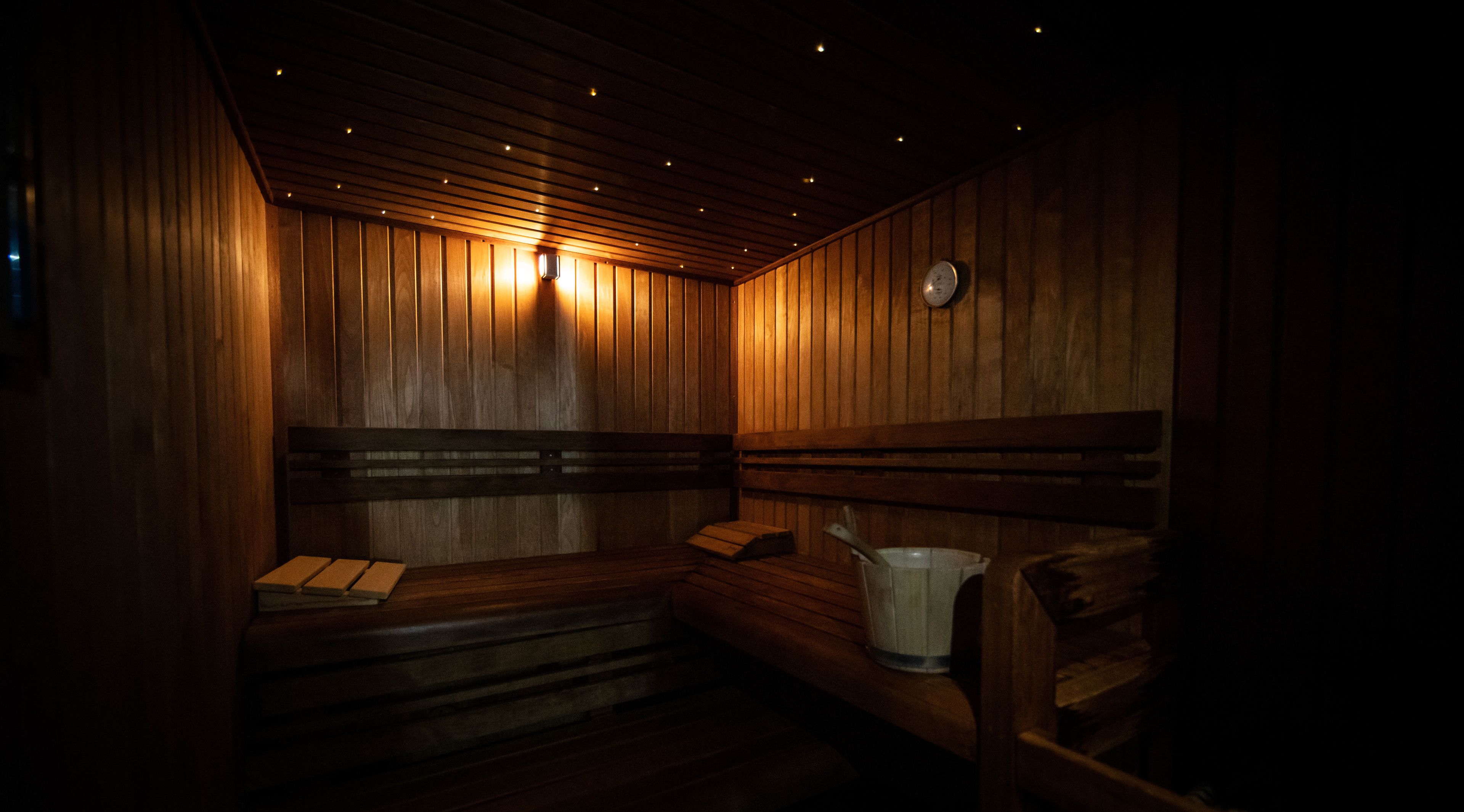 A sauna with wooden benches and a bucket.