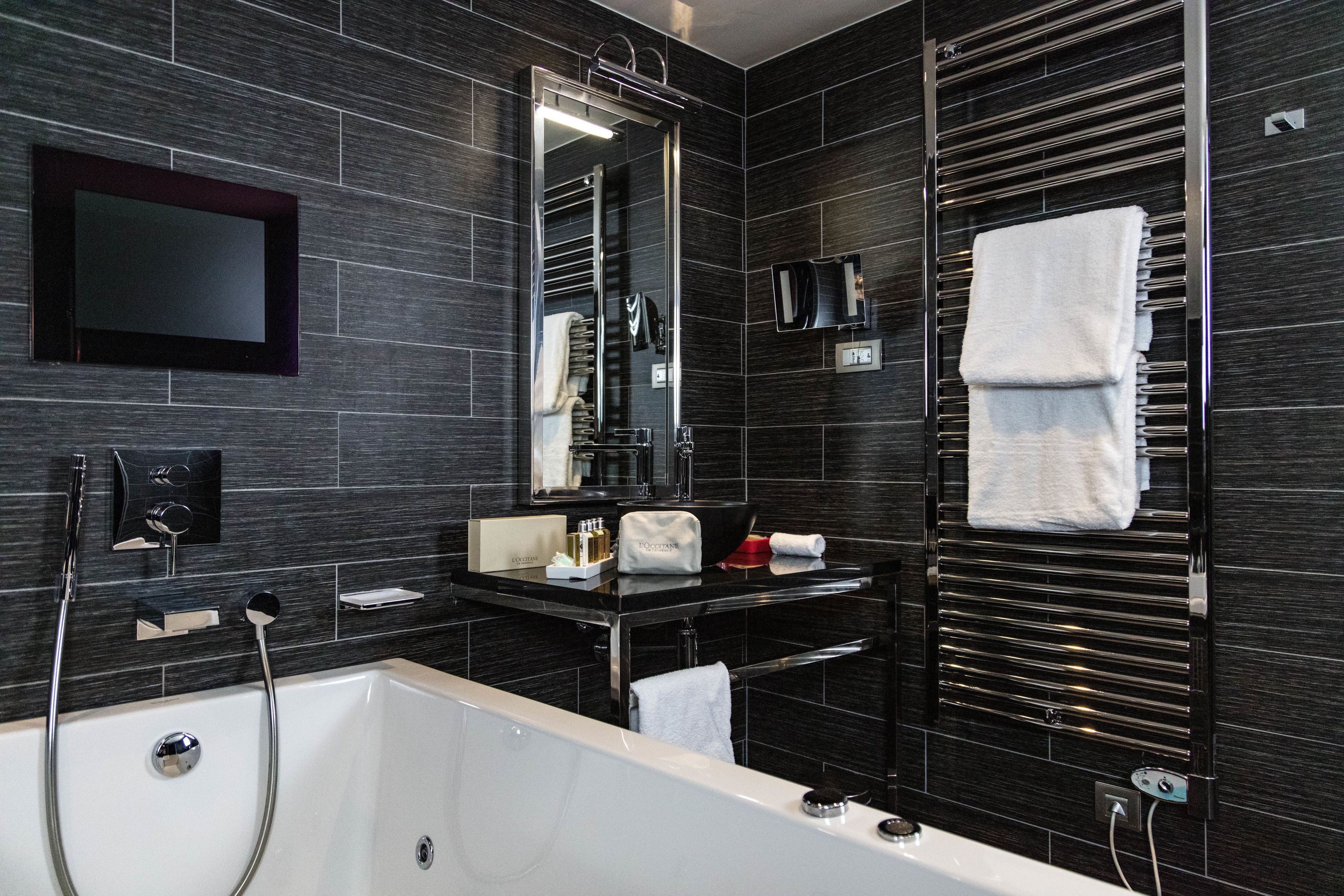 A modern bathroom with a large bathtub, a vanity with a mirror, and a towel rack.