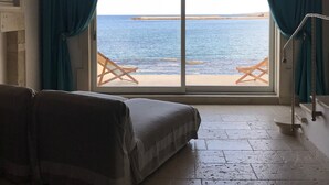 Una habitación con una cama, vista al mar a través de un ventanal grande y techo de madera.