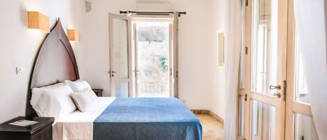 A bedroom with a bed, bedside table, and a view of the outside through a glass door.
