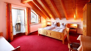 A cozy bedroom with a wooden ceiling, a large bed, a chair, and a window with curtains.
