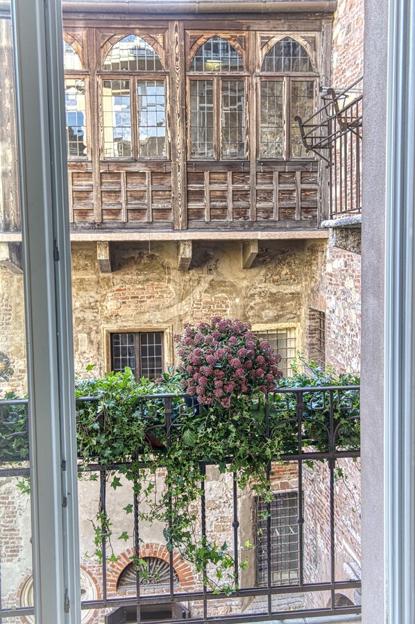 A view of a building with a balcony, a window with a wooden frame, and a brick wall.