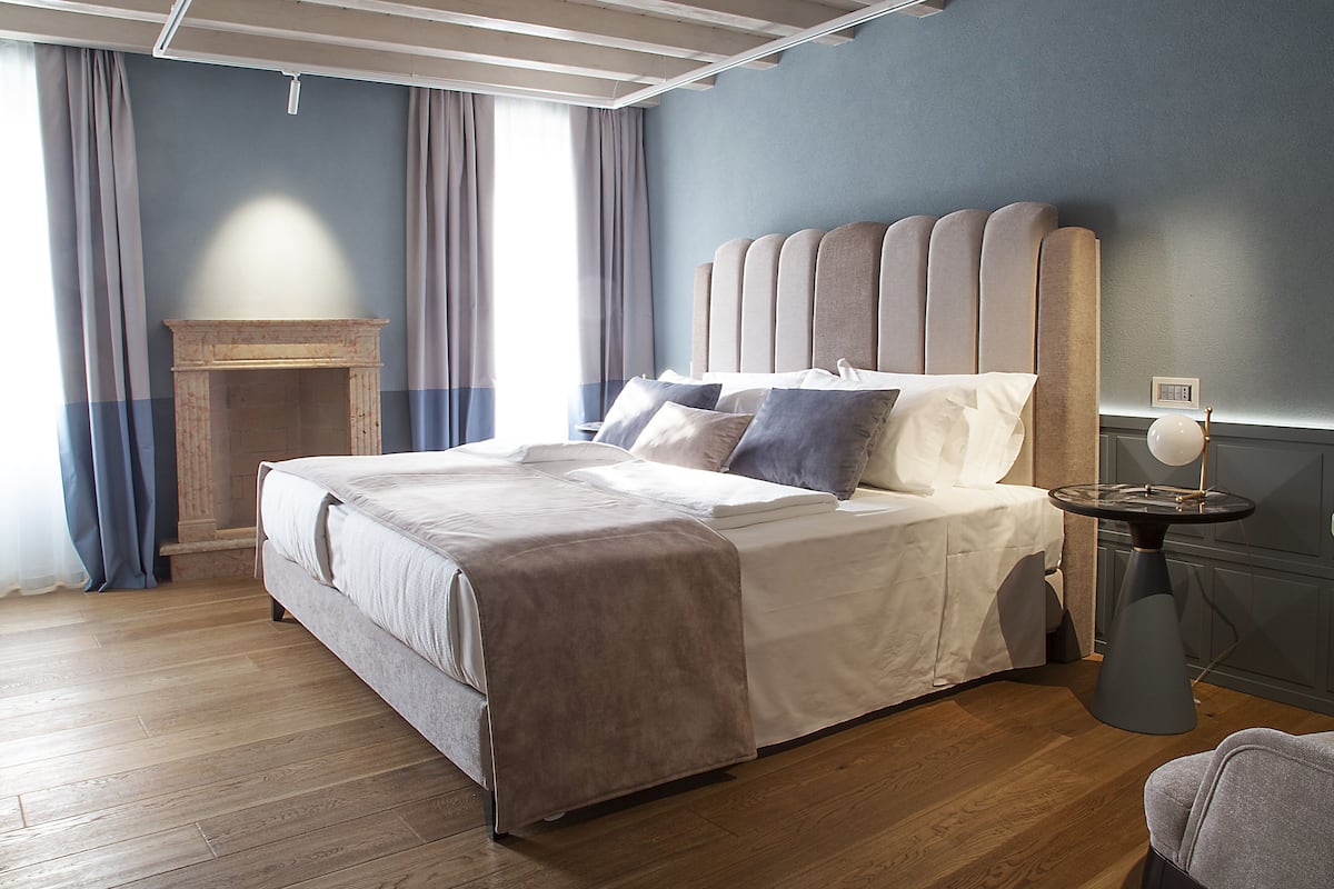 A modern bedroom with a large bed, a small side table, and a fireplace.