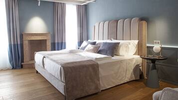 A modern bedroom with a large bed, a small side table, and a fireplace.