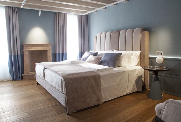 A modern bedroom with a large bed, a small side table, and a fireplace.