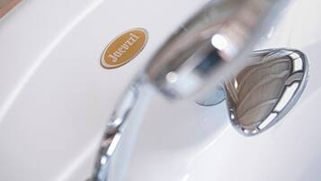 A white sink with a silver faucet and a heart-shaped soap dispenser.