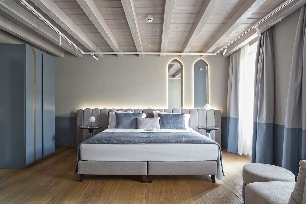 A modern bedroom with a large bed, bedside tables, and a wardrobe.